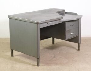 Gray steel tanker desk with an asymmetric top, three drawers, and a lower tray area.