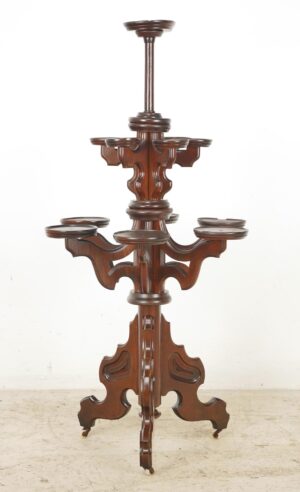 Victorian freestanding plant stand in dark wood tone with spinning tiers, fretwork detailing, and casters, shown full length.