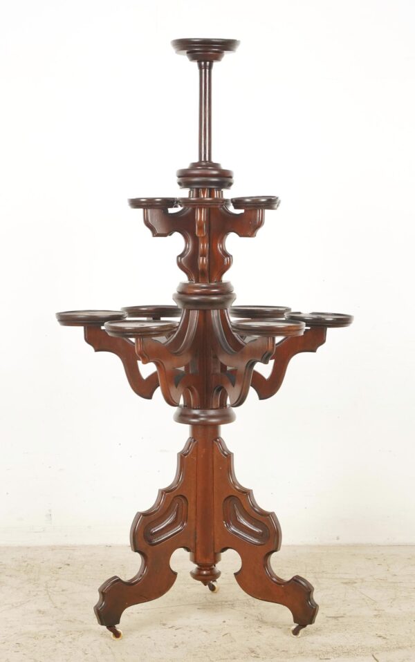 Victorian freestanding plant stand with dark wood tone, multiple round tiers, fretwork detailing, and casters at the base.
