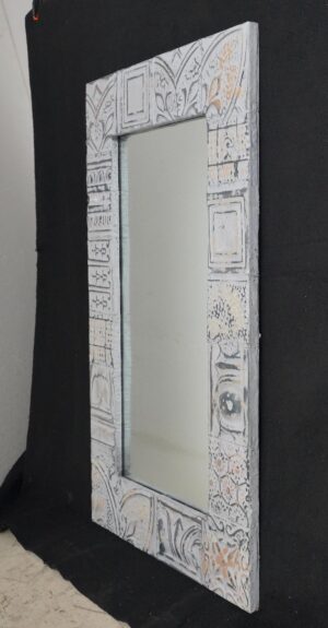 Handcrafted wall mirror with a patchwork tin frame around a rectangular reflective panel.