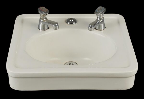 Vintage white ceramic wall sink with an oval basin, chrome faucet hardware, and a center drain opening.