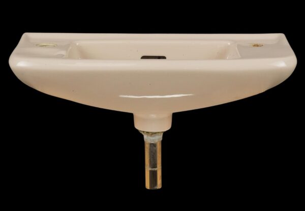 Tan ceramic wall sink with a square basin, side faucet holes, and visible drain hardware.