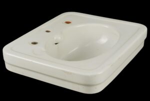 Vintage white ceramic wall sink with an oval basin, three faucet holes, and visible staining and surface wear around the openings and bowl.