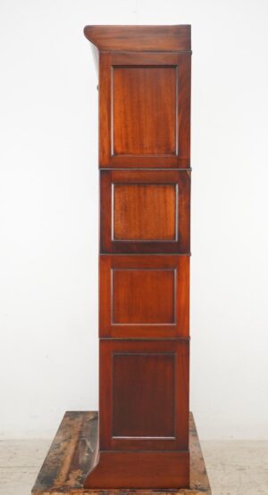 Tall Victorian-style barrister bookcase in dark wood tone, shown closed with stacked paneled sections and a slightly projecting top and base.