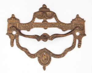 Antique brass drawer pull with ornate Empire detailing and two side screw holes, shown front-facing with a curved handle and decorative center medallion.