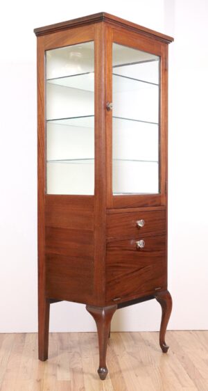 Tall narrow display cabinet with glass front, a lower drawer, and turned legs.
