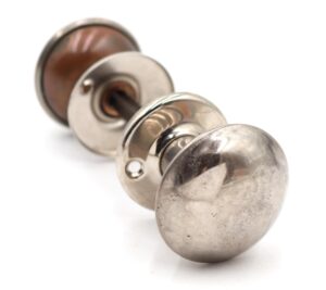 Polished nickel passage door knob set with two knobs, two rosettes, and a spindle shown in a close-up view.