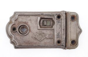 Antique cast iron rim lock with a working latch, shown from the front with four mounting holes and worn gray silver paint.