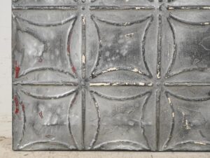 Handcrafted gray tin wall panel with a raised geometric pattern and worn antique finish, shown in a straight-on view.