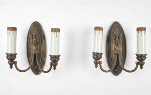 Pair of Federal brass wall sconces with oval backplates, spread-wing eagle centers, and two candle-style arms each.