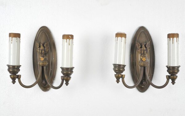 Pair of Federal brass wall sconces with oval backplates, spread-wing eagle centers, and two candle-style arms each.