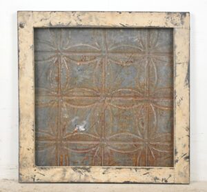 Square wall panel with a weathered wood frame and gray embossed tin center in a geometric pattern.