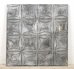 Handcrafted gray tin wall panel with a geometric raised pattern and worn antique finish.
