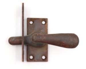 Vintage brass casement latch with a dark antique finish, shown in close-up with the handle and rectangular backplate.